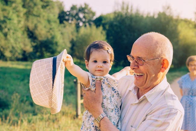 Grandfather holding a young child, representing family caregiving and guardianship responsibilities.