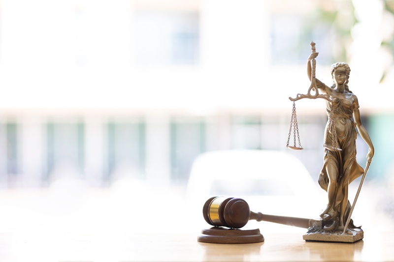 A sunny office and desk area with a judges gavel and a small statue of Lady Justice.