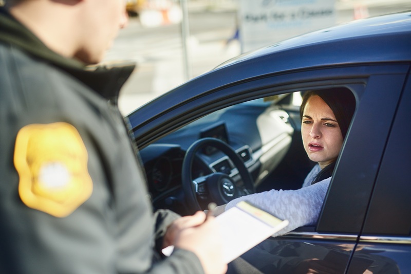 A woman is receiving a traffic violation which may involve suspension of her driver's license.